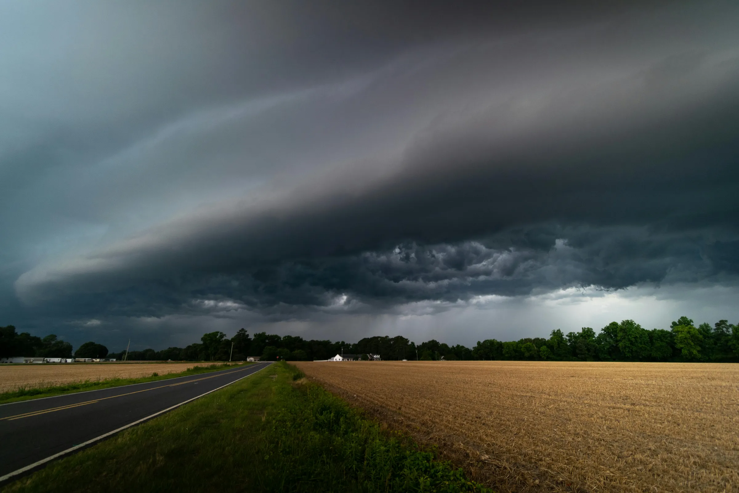 Arcus shelf cloud menaçant au-dessus d'une route et d'un champ, l'orage déjà sur vous